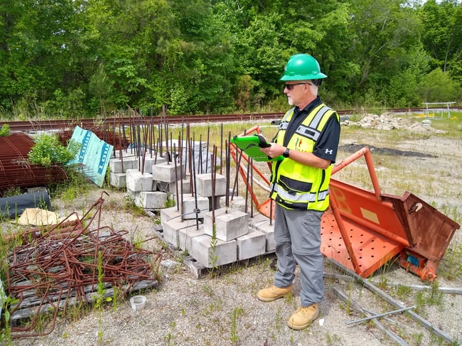 Phase I ESA costs consultant in safety vest with clipboard conducting Phase I ESA