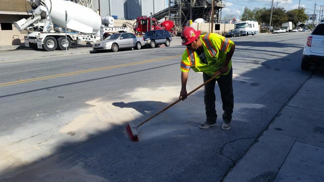 industrial employee sweeping ground with broom