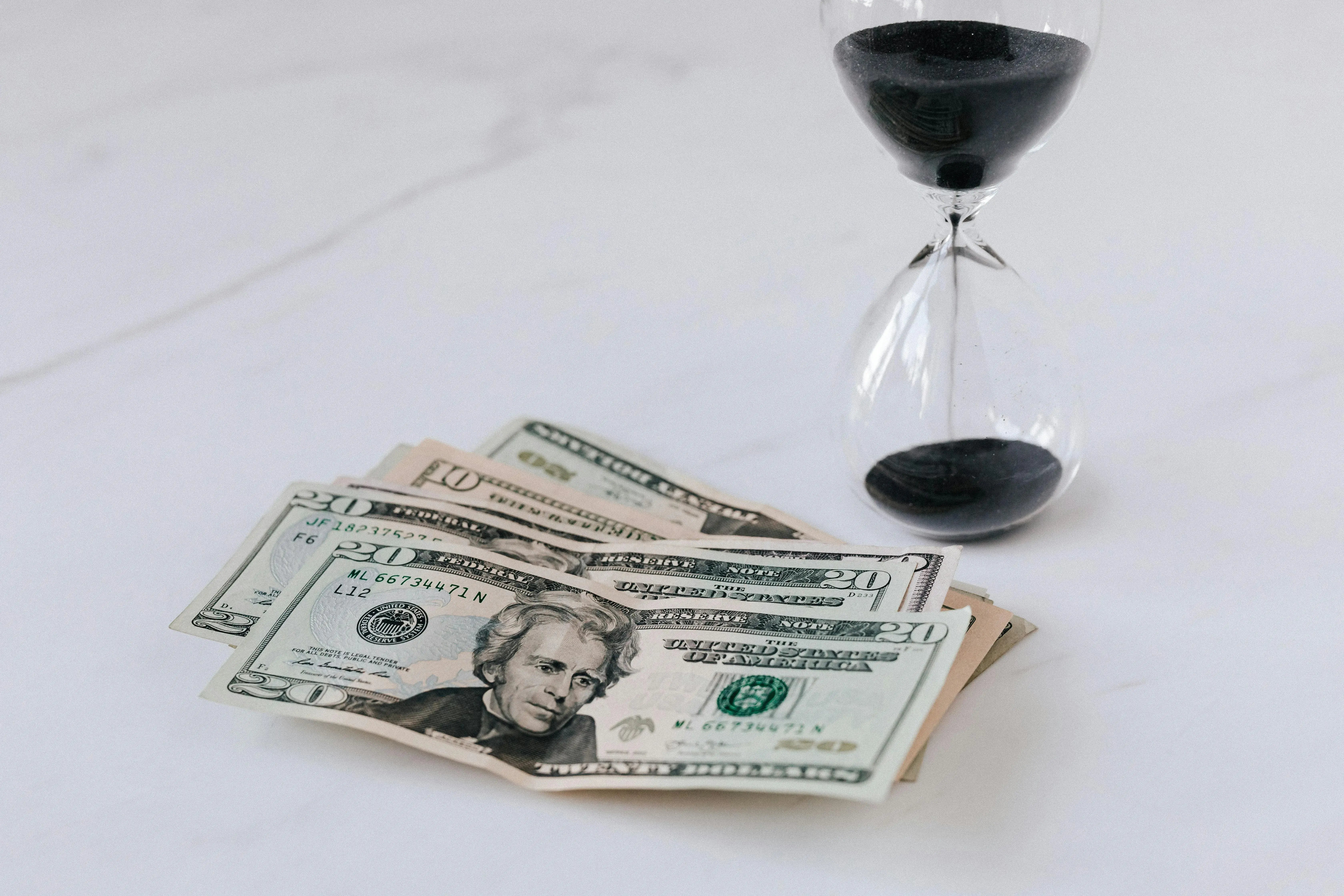 dollar bills next to hour glass
